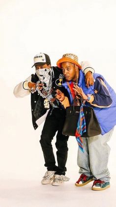 two young men standing next to each other in front of a white background, one with his arms around the other's neck