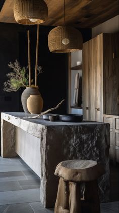 a kitchen with black walls and stone counter tops, two hanging vases above the island