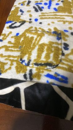 a close up of a table with a yellow and blue pattern on it, next to a wooden floor