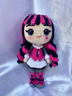 a crocheted doll is posed on a white background with pink and black accents