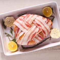 a large piece of meat is wrapped in bacon and garnished with lemon slices