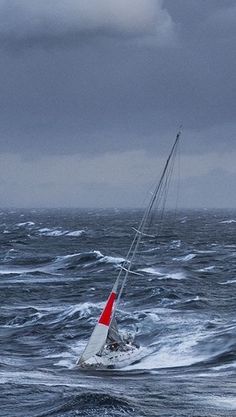 a sailboat in the middle of choppy ocean water on a cloudy day with storm clouds