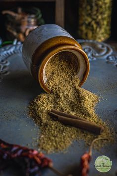 an open jar filled with spices sitting on top of a metal tray next to chili peppers