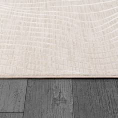 an area rug with wood flooring on top of it and a white wall in the background