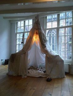 a white bed sitting on top of a hard wood floor next to two large windows