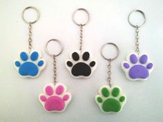 four different colored paw prints are shown on the keychains, one is black, one is white and one is pink