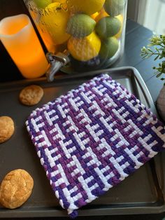 a tray with cookies and lemons on it next to a vase filled with oranges