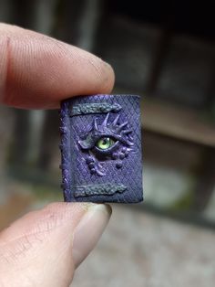 a hand holding a small purple object with an eye on it