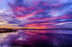 the sky is reflected in the water at sunset