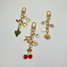 two key chains with charms attached to them on a white surface, one is gold and the other is red