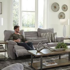 a man sitting on a couch in a living room with a coffee table and sofa