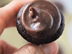 a close up of a person holding a chocolate cookie with the frosting on it