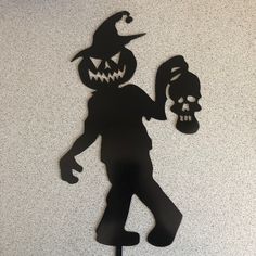 a black silhouette of a person holding a skull and a jack - o'- lantern