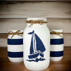 three painted mason jars sitting on top of a wooden table covered in twine rope