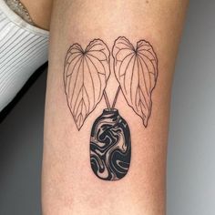 a woman's leg with a tattoo on it that has two leaves in the vase