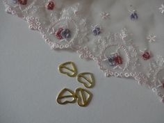 two pairs of gold rings sitting on top of a white lace covered table cloth next to some scissors