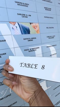 a person holding up a piece of paper with the name table 8 printed on it