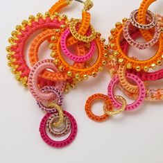 two pairs of multicolored beaded hoop earrings on white surface with gold accents