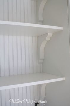 two white shelves in the corner of a room