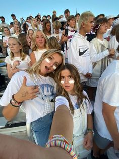 two girls giving thumbs up in front of a crowd