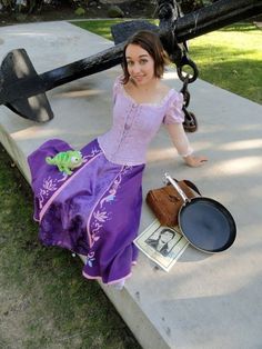 a woman in a purple dress sitting on the ground next to an old fashioned cannon