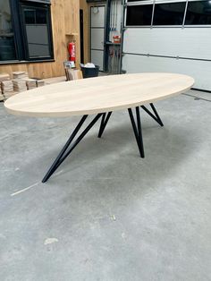 an oval table with black legs in a garage