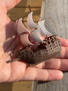 a hand holding a small model ship in it's palm