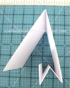 an origami paper airplane sitting on top of a cutting mat