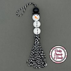 a snowman ornament with a black and white tassel