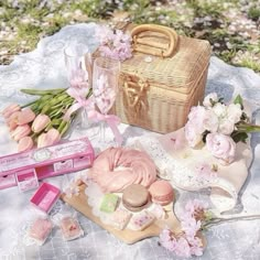 a picnic table with flowers, cookies and other items on it in the grass near a basket