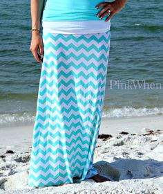 a woman is standing on the beach wearing a blue and white chevroned skirt