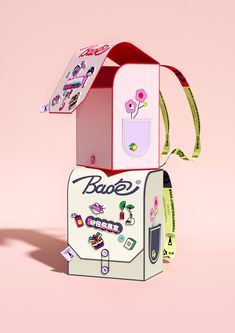 an open box with stickers on it sitting on top of a pink surface next to a paper bag