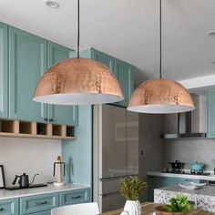 two pendant lights hanging over a kitchen table with blue cabinets and white chairs in front of it