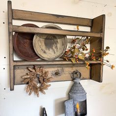 an old wooden shelf with some plates on it and other items hanging from the wall