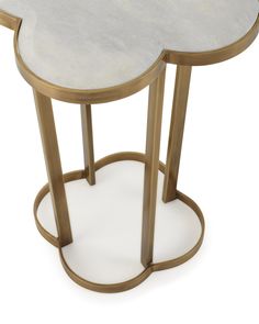 a white and gold side table with an oval design on the top, in front of a white background