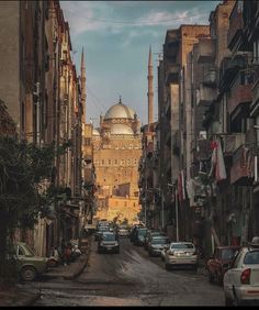 an old city street with cars parked on both sides and tall buildings in the background