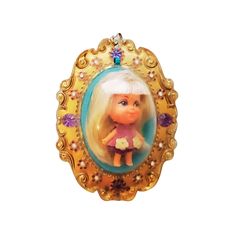 an ornament shaped like a girl with blonde hair wearing a pink dress and holding a flower in her hand