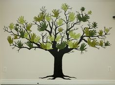 a large tree with green leaves on it's branches is painted on the wall