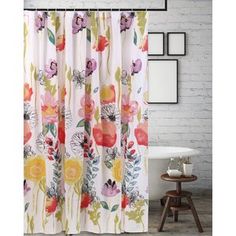 a shower curtain with flowers on it in front of a white brick wall and floor