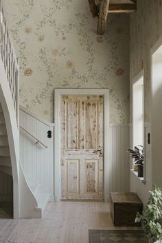 an entryway with floral wallpaper and wooden steps leading up to the front door