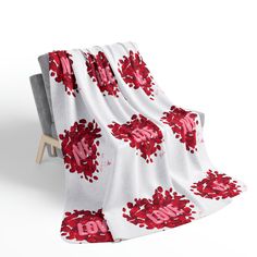 a white blanket with red flowers and the word love on it is draped over a chair