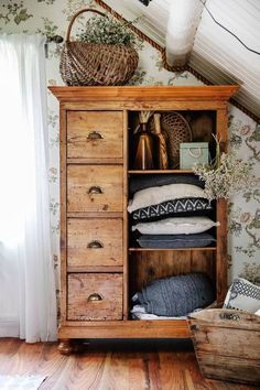 an old wooden cabinet with pillows and baskets on top