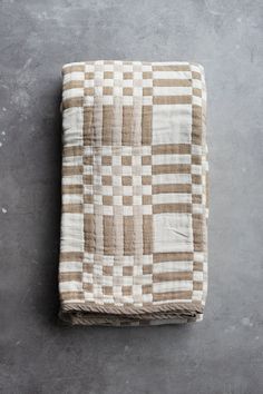 a brown and white checkered blanket sitting on top of a cement floor next to a gray wall