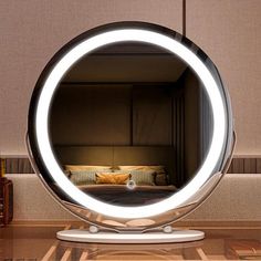 a round mirror sitting on top of a wooden table next to a bed in a room