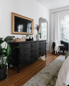 a living room with a black dresser and large mirror in it's centerpiece