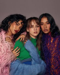 three models pose for the camera with their arms around each other and one is wearing a green sweater