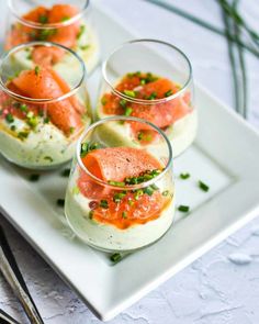 three small glasses filled with food on top of a white plate