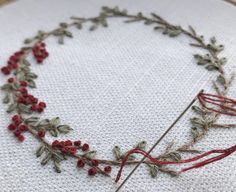 a close up of a piece of embroidery on a white cloth with red flowers and leaves