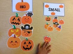 a child's hand pointing at pumpkins on a bulletin board with small stickers