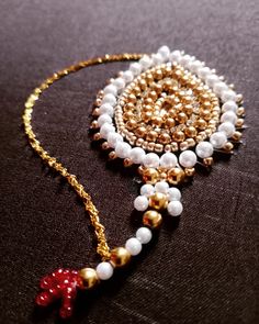 the beaded necklace is decorated with beads and a red bow brooch on it